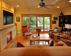 By relocating the fireplace to an adjacent wall and opening that West wall to a large sliding door, the change is transformative. Not only is light from those doors clearly visible down to the home's entry, but the 4-panel sliding door opens the view of the room to the outdoors, making it feel larger
