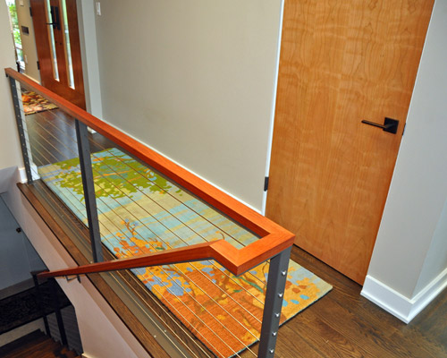 The stainless steel cables with powder-coated steel posts affirm the contemporary design, and the Brazilian cherry cap reflects the intent of wood species selection for the doors