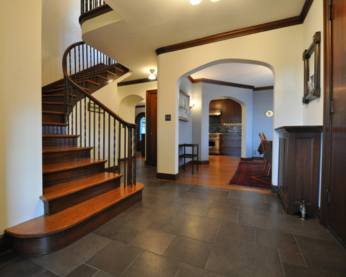 Remodeling at the front door creates a grand entry.  Porcelain tile in an offset pattern is understated and beautiful.  Now the main floor is appropriate to the era of the house, elegant and functional. Remodel Seattle Tudor style