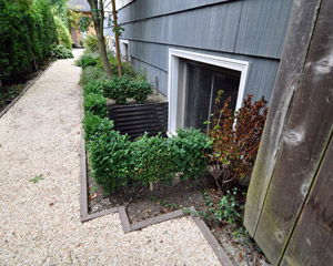 From the outside, new shrubbery delineates and will soon conceal the window wells.  Siding and window replacement at the main floor is the next planned project
