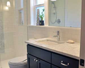 The vanity is in a dark-stained wood, and a matching linen cabinet is tucked across from it behind the door