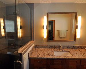 The cherry vanity by Kitchencraft is laid out with more functional drawers and doors, and the new electrical plan provides much better lighting for the room in this remodel Seattle rambler