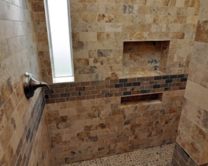 Inside the shower, a generously sized niche provides lots of space for shampoo and soaps.  The controls for the shower are at the left, which allows a warmup of the water without getting wet first.  The shower floor is pebbles with natural stone on all walls