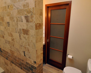 Exiting the shower, you can see the new mahogany pocket door, also with obscured glass.   The slat floor tiles pick up the colors in the wood with hints of wood grain