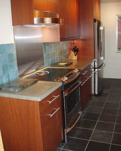 The warm wood tones of the cabinets mix well with the steel accents of the appliances.  New slate tile flooring in the kitchen, extends to the front door