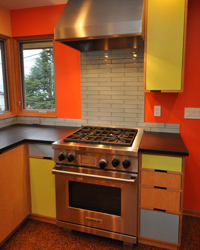 The clear centerpiece of the kitchen, though, is the Wolf range, particularly because it is visible from all the common rooms. The stainless hood anchors it along with a small upper cabinet. There was talk of using a stainless backsplash, but the clients opted for more of the glass backsplash tile instead.  Epoxy grout was used to make it as easy to clean as possible