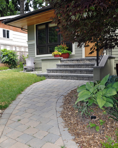 A concrete walk was removed to install a new curving paver pathway to the front door, the width of the new front porch