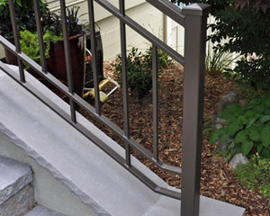 The porch is built with concrete footings, CMU, finished with pavers and caps, and stucco on the vertical sides.  Stucco in a darker green color is also a feature in the two-part siding, which combines with Hardiplank cement siding, divided by a wood belly band.  The new fiberglass entry door and natural wood soffits completes the look